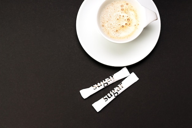 Tasse De Café Cappucino Avec Des Sachets De Sucre Blanc Sur Table Noire.