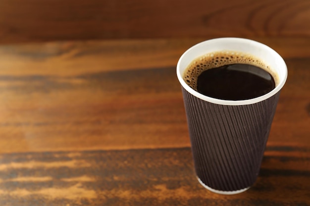 Tasse de café en carton sur fond de bois