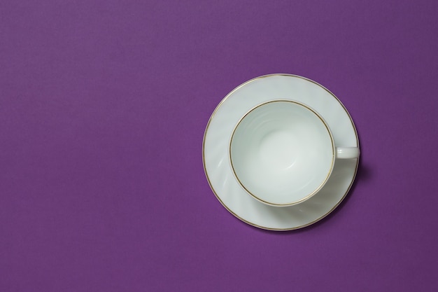 Tasse à café en céramique blanche sur fond lilas. Plats pour boissons chaudes. Mise à plat.