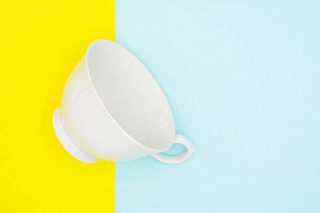 Tasse à café en céramique blanche sur papier bleu et jaune - fond