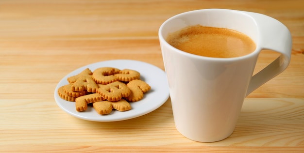 Tasse de café chaud avec une assiette de biscuits sur table en bois
