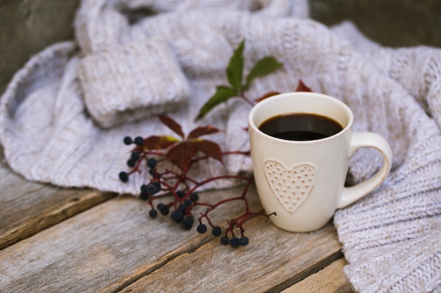 Tasse de café chaud à l'automne sur une table en bois avec une écharpe tricotée, pull