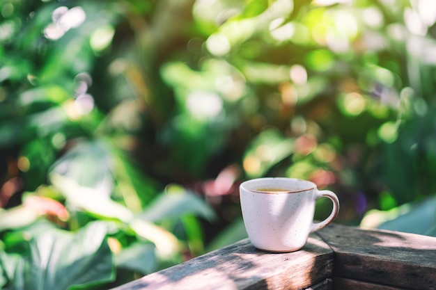 Une tasse de café chaud sur un balcon en bois dans le jardin