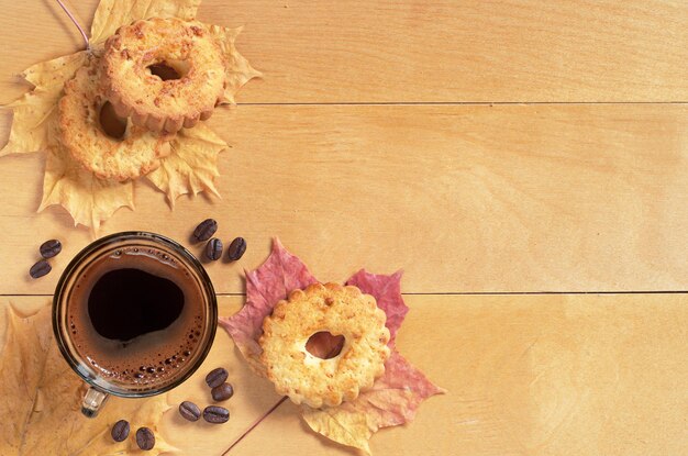 Tasse de café chaud et biscuits anneaux avec des cacahuètes sur la vue de dessus de fond en bois jaune