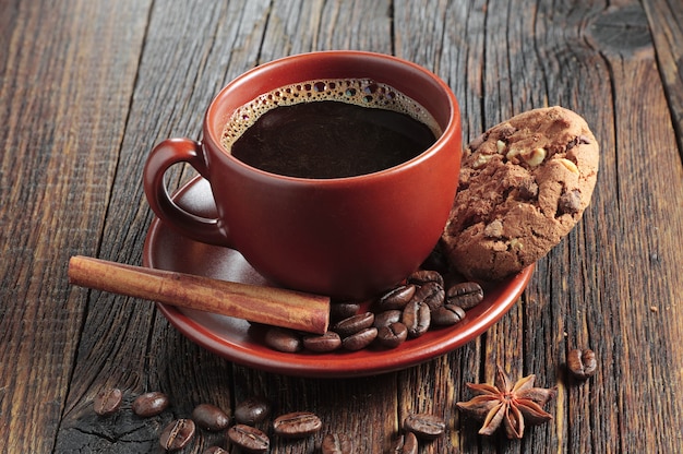 Tasse de café chaud et biscuits au chocolat avec noix en argile brune sur table en bois