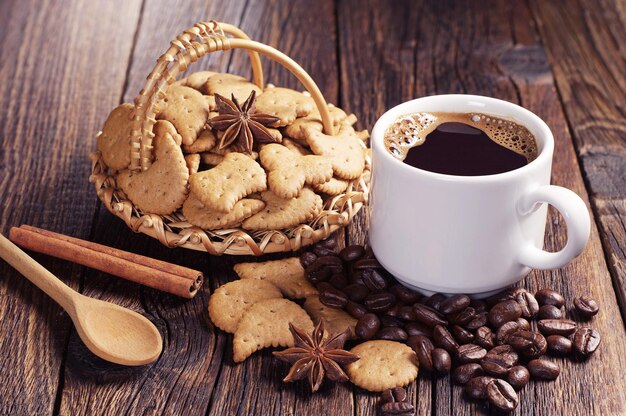 Tasse de café chaud et biscuits de Noël dans un panier en osier sur une vieille table en bois