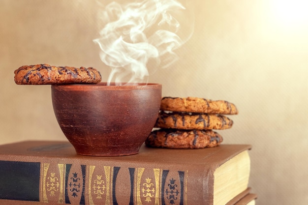 Tasse de café chaud et biscuits sur une pile de livres dans une bibliothèque ou une étude