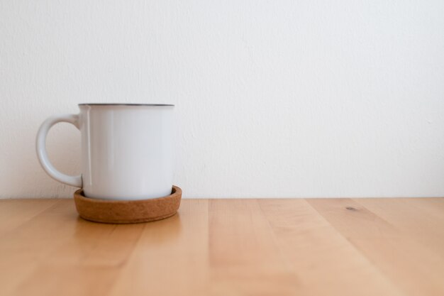 Tasse à café chaud blanc sur table en bois et mur blanc avec espace de copie.