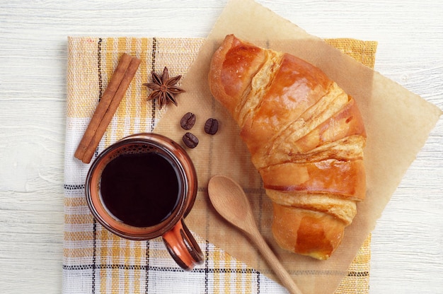 Tasse de café chaud et croissant savoureux sur nappe jaune, vue de dessus