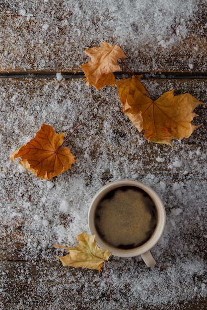 Tasse de café chaud debout sur la neige avec des feuilles jaunes. Concept de mode de vie en plein air. Détendez-vous et reposez-vous. Fermer.