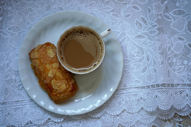 Une tasse de café chaud avec du pain aux amandes danois sur la table