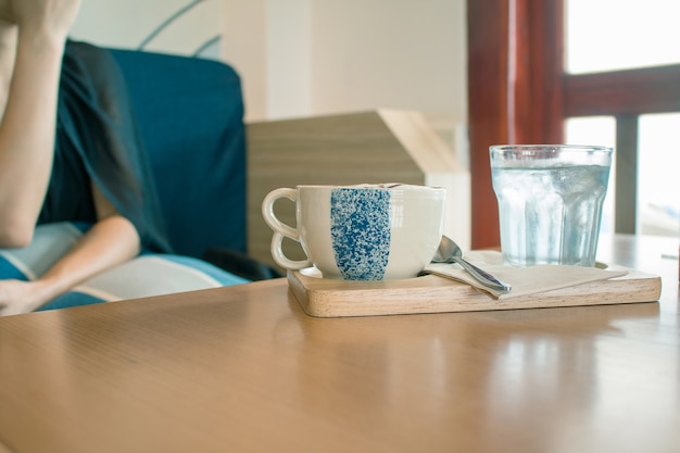 Une tasse de café chaud avec une femme floue sur le fond.