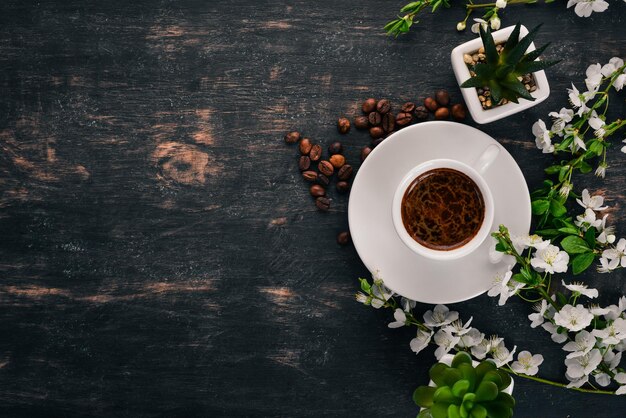 Une tasse de café chaud avec des fleurs Sur un fond en bois Vue de dessus Espace de copie