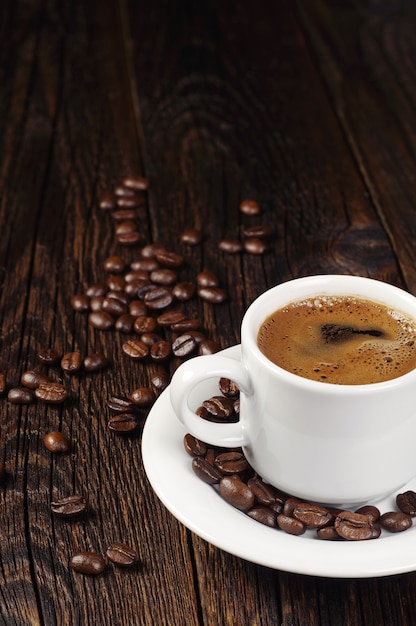 Tasse de café chaud et grains de café sur table en bois