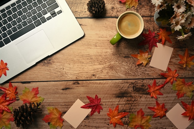 Tasse de café chaud, ordinateur portable et feuilles d'érable d'automne sur fond en bois.