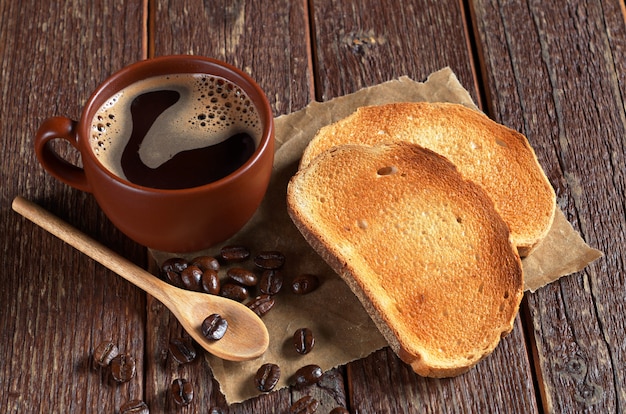 Tasse de café chaud et pain blanc torréfié sur la vieille table en bois