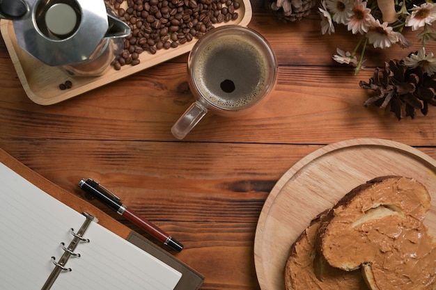 Une tasse de café chaud et sandwich au beurre d'arachide sur table en bois.