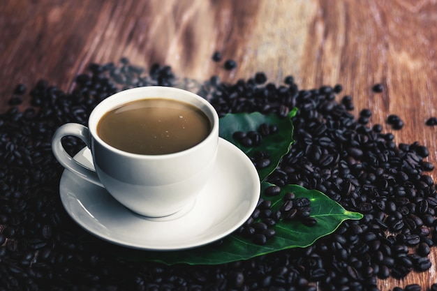 La tasse de café chaud sur la table en bois a un peu de fumée.