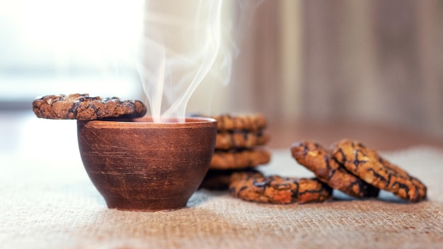 Tasse de café chaud ou de thé et de délicieux biscuits sucrés sur la table près de la fenêtre