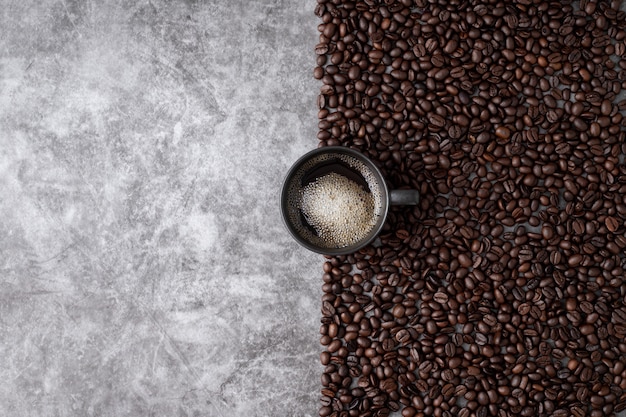 Tasse à café chaude avec des grains de café sur fond de mur de ciment.