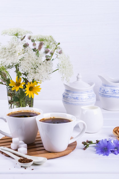 Tasse de café chicorée thé boisson boisson chaude avec fleur de chicorée et biscuits au sucre sur un tableau blanc. Nature morte avec petit déjeuner