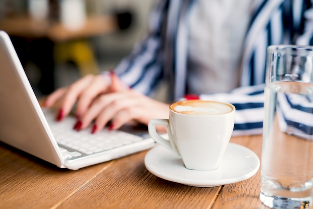 Tasse de café ciblée pendant que la femme d'affaires fait une pause dans un café.