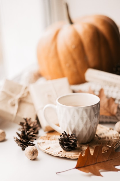 Tasse de café, citrouille, feuilles d'automne séchées sur la fenêtre.