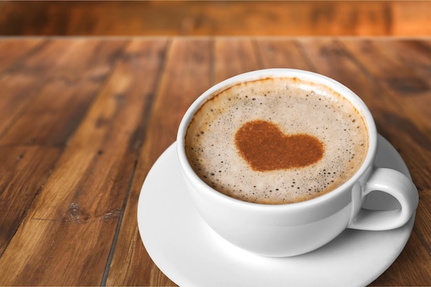 Tasse de café avec coeur sur plaque sur fond de table en bois