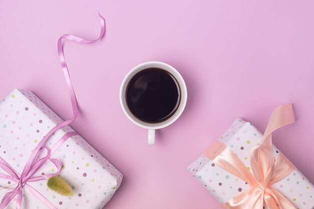 Tasse de café et coffrets cadeaux fond rose fête de vacances vue de dessus horizontale