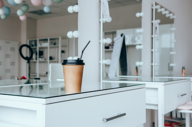 Une tasse de café sur la coiffeuse près du miroir dans la salle de maquillage