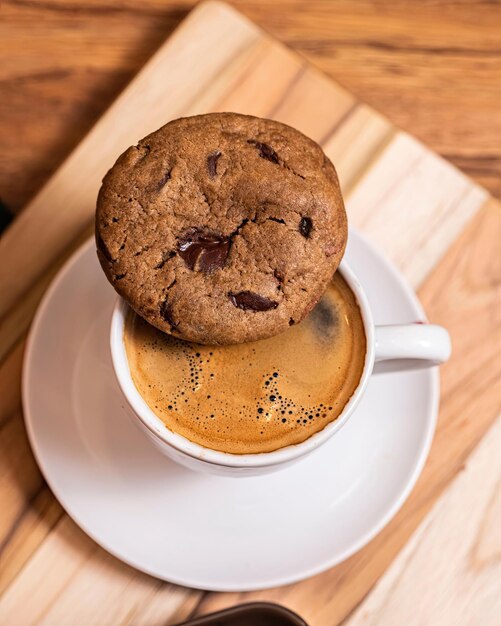 Une tasse de café avec un cookie aux pépites de chocolat sur le dessus