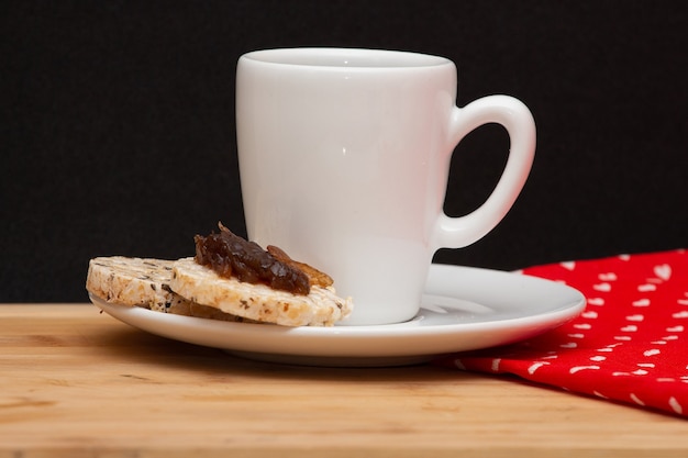 Une tasse de café à côté d'une cuillère et un biscuit végétalien de riz avec une gelée sur le dessus