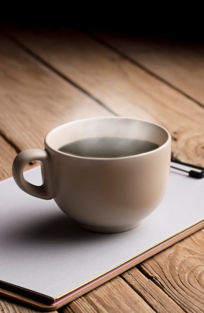 tasse de café de couleur beige douce avec de la vapeur chaude et un ordinateur portable sur une table en bois rustique