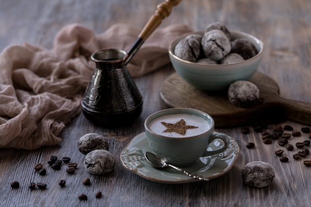 Tasse de café Crema avec biscuits aux pépites de chocolat, guimauves et bougies allumées.