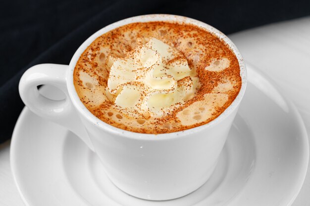 Tasse de café avec de la crème fouettée sur tableau blanc