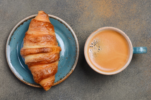 Tasse de café avec croissant sur béton