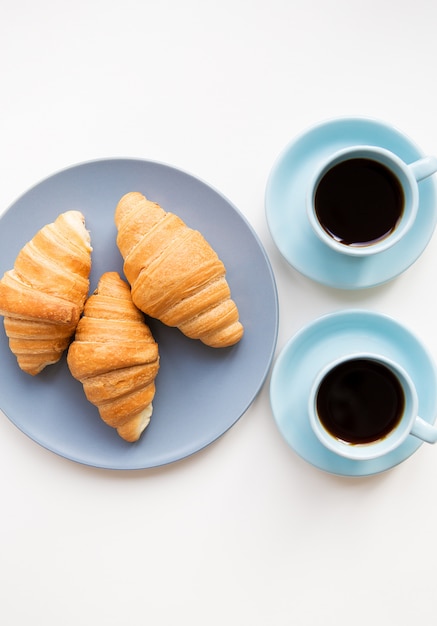 Tasse de café avec croissant sur fond blanc