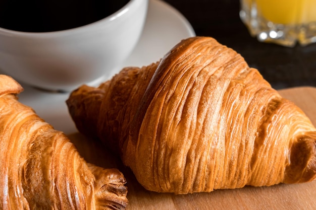 Une tasse de café et un croissant sur une planche de bois