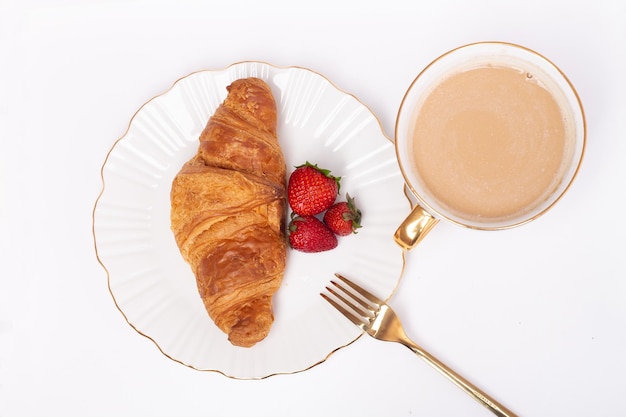 Tasse à café et croissant sucré avec fraise fraîche sur tableau blanc