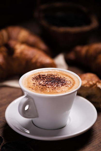 Tasse à café avec un croissant sur une table en bois rustique clse up