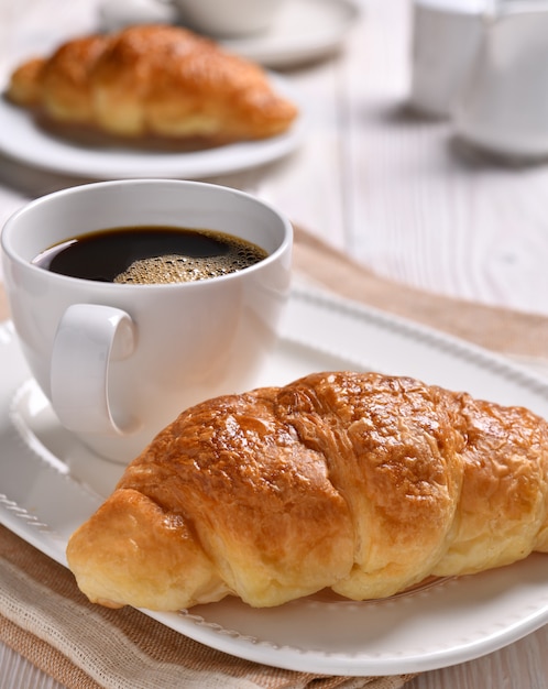 Une tasse de café et un croissant sur une table en bois