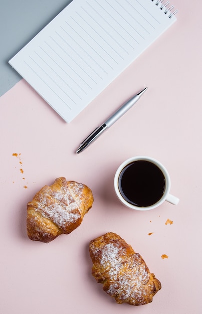 Tasse à café avec croissants et bloc-notes pour plan d&#39;affaires et idées de design sur fond bicolore