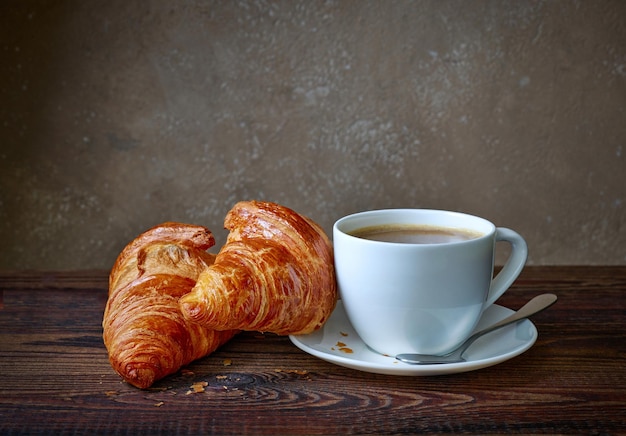 Tasse de café et croissants sur table de cuisine en bois