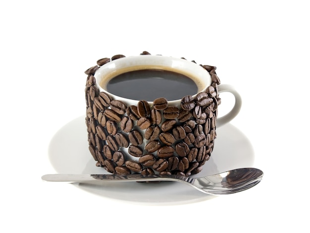 La tasse de café et la cuillère, décorée de grains de café. Isolé