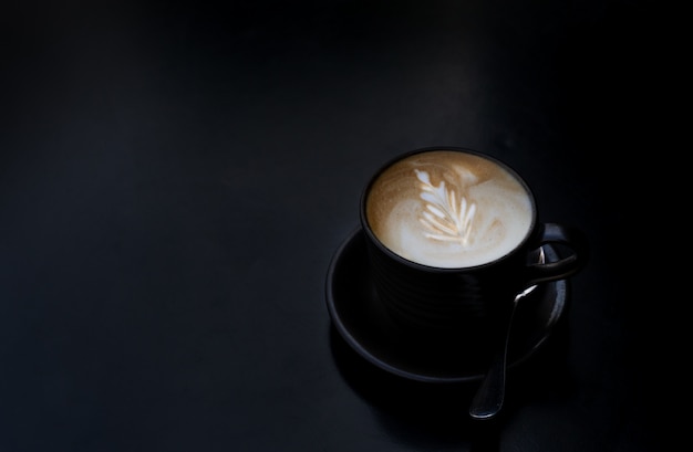 Tasse à café avec une cuillère sur fond sombre.