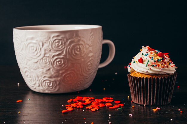 Tasse de café avec cupcake cœur saupoudré.