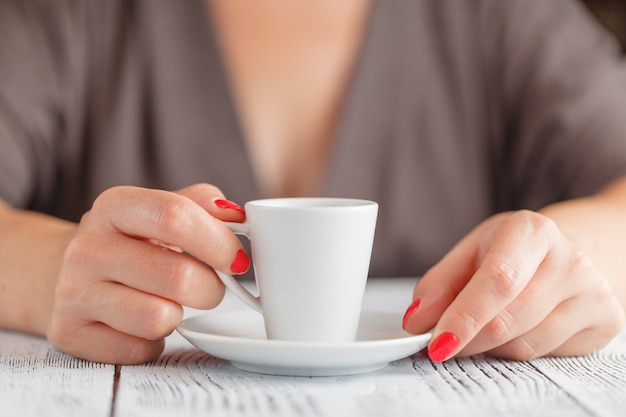 Tasse de café dans la main des femmes sur la table