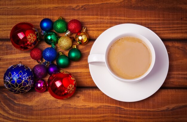 Tasse de café et différentes bulles de Noël sur fond en bois.