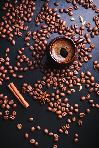 Tasse de café avec une dispersion de grains de café sur une sombre