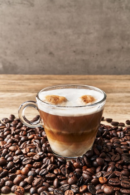 Une tasse de café avec du lait et des grains de café sur une surface en bois